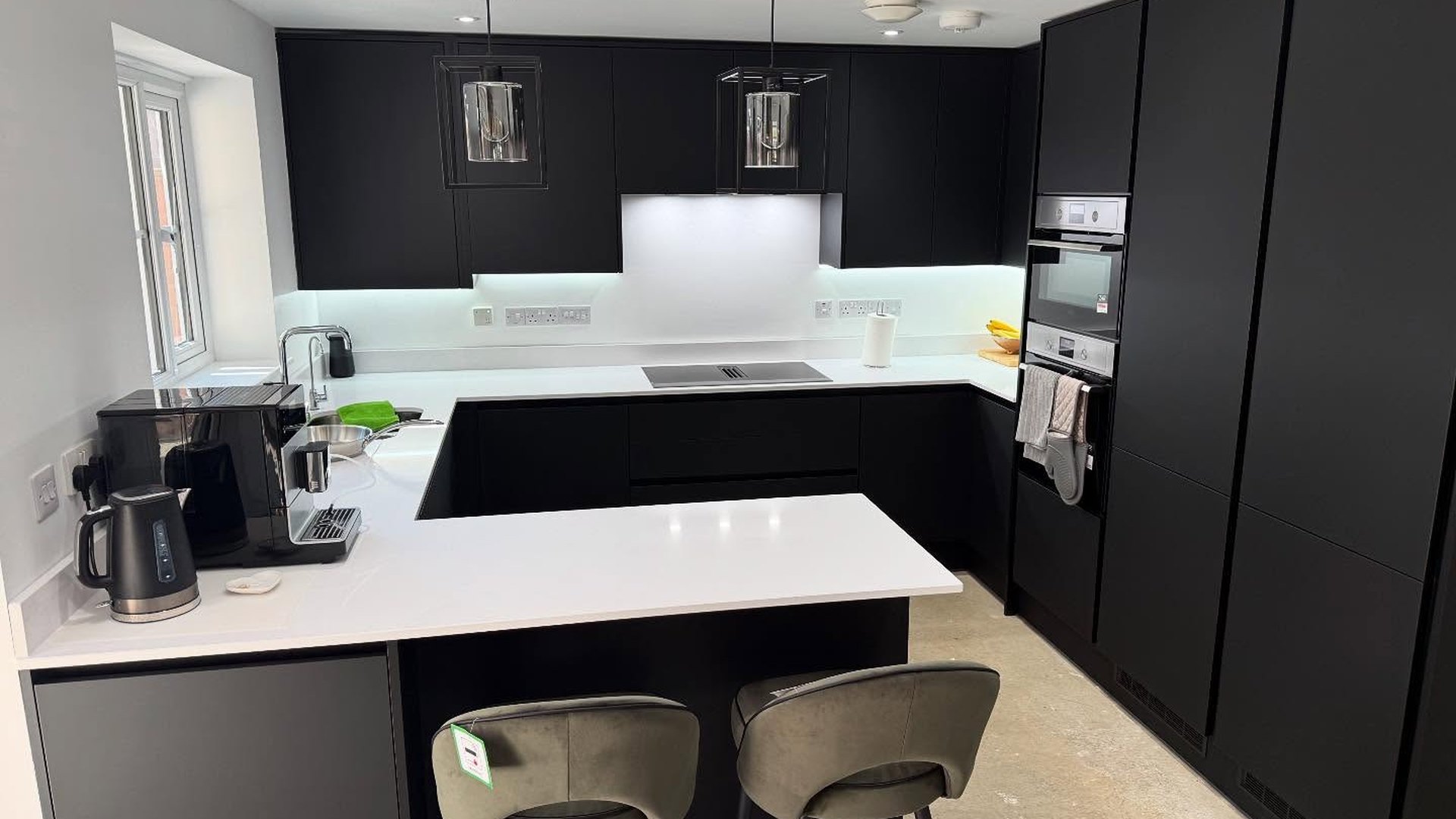 Matt black kitchen with white quartz worktops and a breakfast peninsula