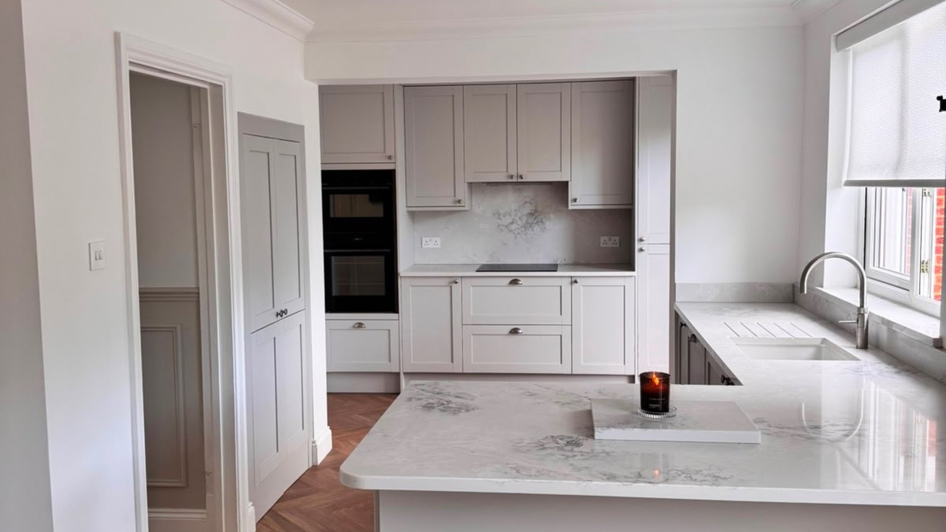 Shaker kitchen with a marble effect peninsula and herringbone parquet flooring
