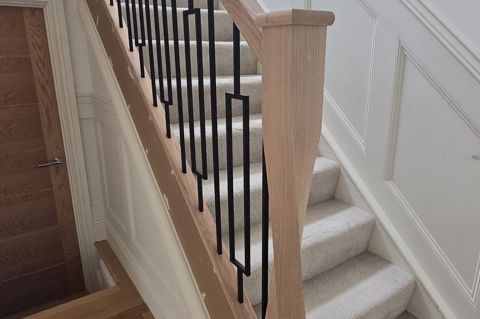 Renovated staircase with a new oak handrail and black metal spindles